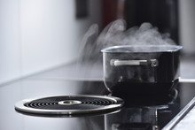 Modern Electric Induction Cooker With Built-in Ventilation And Extractor Hood Which Draws Steam From Boiling Water In A Pan. Steam From A Boiling Pot Is Drawn Into The Integrated Range Hood