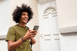 © mimagephotos - Close up happy young man holding mobile phone and walking outside