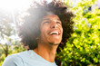 © mimagephotos - Close up handsome young North African man with afro hair laughing outside