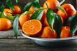 Fresh Clementine Mandarin Oranges fruits or Tangerines with leaves on wooden background