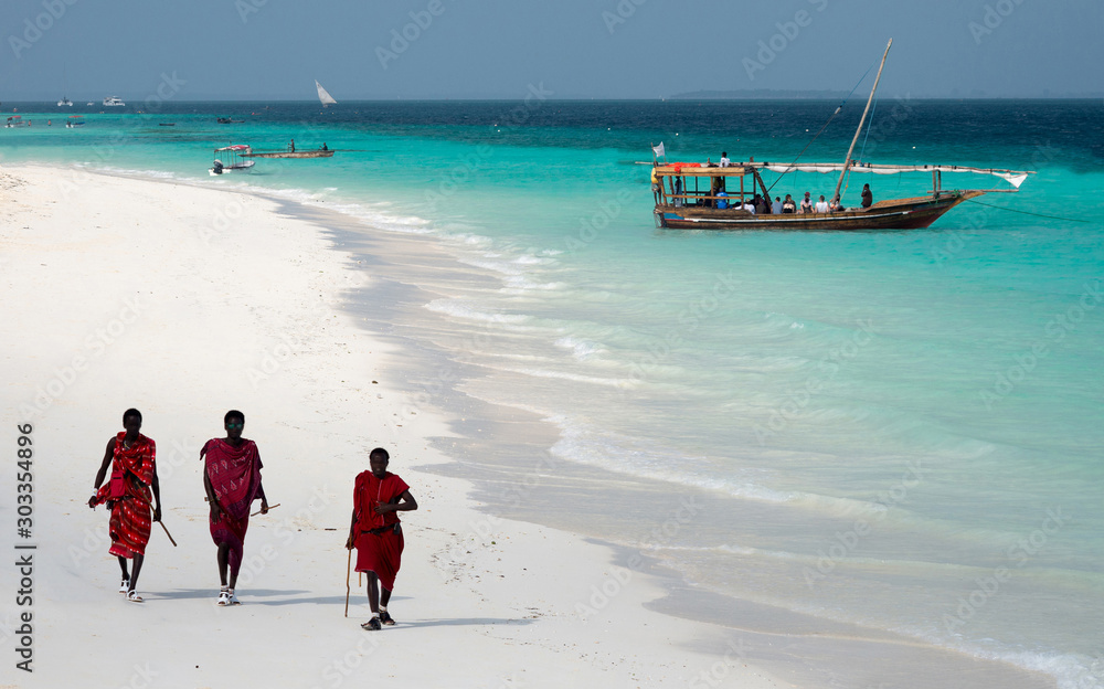 Masai, entertaining tourists on the beach in Nungwi. Zanzibar, Tanzania, East Africa. - obrazy, fototapety, plakaty 