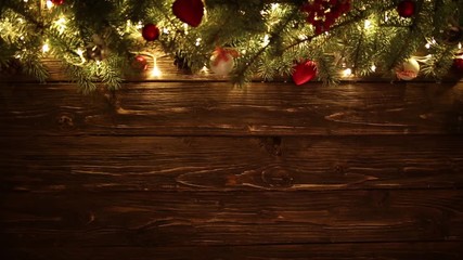blurred christmas background, with fir branches, fairy lights and christmas decorations on brown woo