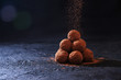 Homemade Chocolate Truffles in Glass with Sifting Cocoa on Dark Stone Table and Background. Copy Space