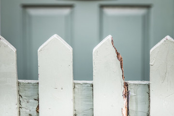 Light teal coloured fence with a broken picket