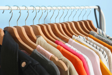 Wall Mural - fashionable clothes on hangers on a wardrobe rack on a colored background.