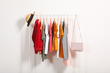 Wall Mural - Fashionable clothes on hangers on a wardrobe rack on a light background.