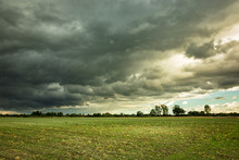 Black Stormy Clouds Over A Green Field