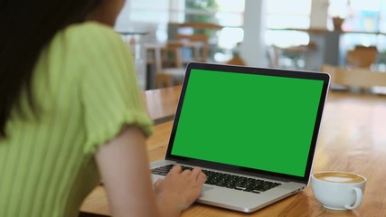 over the shoulder shot of a business woman working in office interior on pc on desk, looking at gree