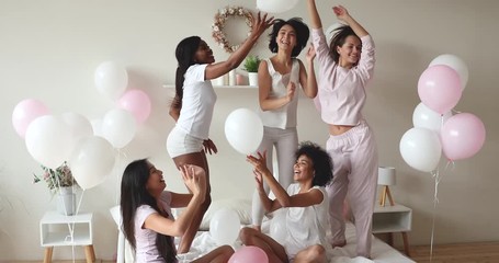 Wall Mural - Excited sexy diverse ladies dancing on bed celebrate with balloons