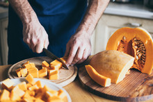 Man Cuts Pumpkin In The Kitchen