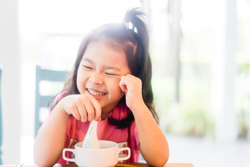 Wall Mural - 5 years old asian girl eating hong kong congee or rice porridge on breakfast time.Happy time in breakfast with asian food everyday.