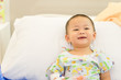 © MIA Studio - Sick child baby boy lying in bed with a fever and smile in the bed at hospital.