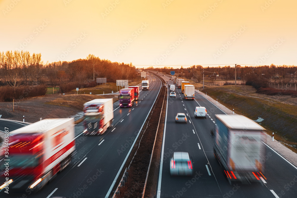Busy highway with fast moving vehicles in beautiful sunset - obrazy, fototapety, plakaty 