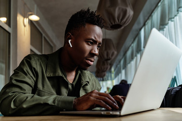 Poster - african american man using computer in cafe. young businessman working on his laptop