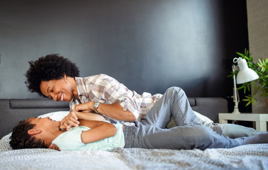 Wall Mural - Happy mother playing, having fun, hugging with her son at home