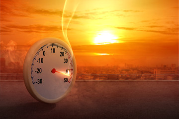 Wall Mural - The thermometer on the street with a high temperature on the city with a glowing sun background