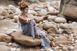 © zolotareva_elina - young fashionable woman sitting on the stone beach