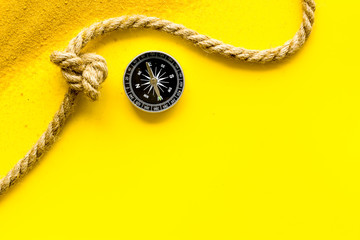 Wall Mural - Goal achievement concept. Compass near rope with knot on yellow background top view copy space