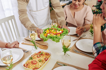 Poster - Cropped image of man bringing dishes to Christmas family dinner table