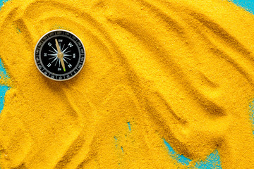 Wall Mural - Travel concept. Compass on yellow sand background top view copy space