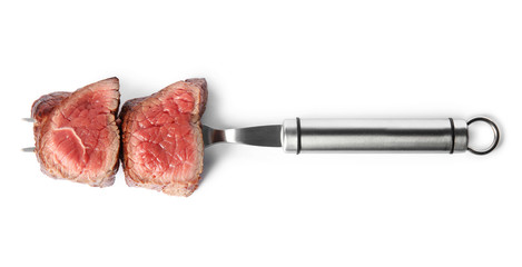 Carving fork with slices of delicious beef tenderloin isolated on white, top view