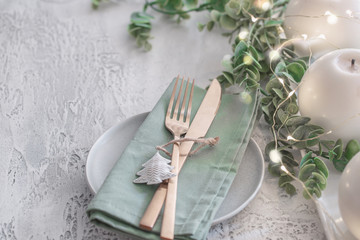 Wall Mural - Nordic Festive tableware for Christmas and New Year celebration. Gold cutlery and green linen napkin on cement background. Kinfolk style