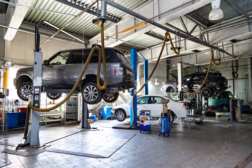 Hree Used Cars With An Open Hood Raised On A Lift For Repairing