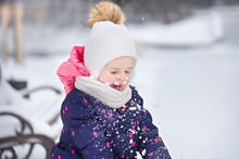 Cute Baby Girl Playing Outdoor With Fresh White Snow In Winter Snowy Park. Horizontal Color Photography.