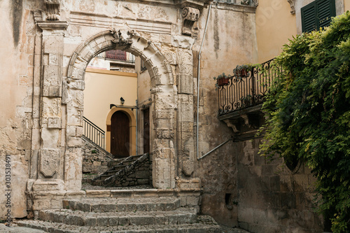 Fotomural ancient arch in old building near green plants in modica, italy