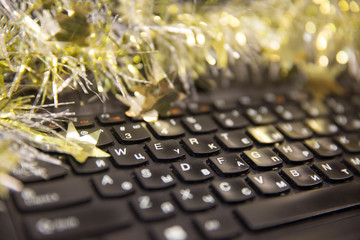 Keyboard with english and russian letters. On top of the keyboard is shiny tinsel.