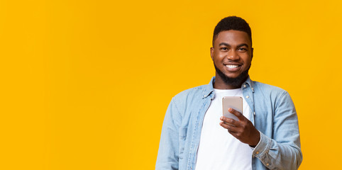 Wall Mural - Portrait of smiling black guy with smartphone in hands