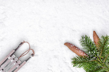 Wall Mural - Christmas background with snow, sleigh, christmas pine branch and pine cones, flat lay, top view