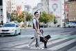 © Halfpoint - Young blind man with white cane and guide dog walking across street in city.