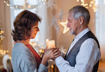 Wall Mural - Side view of happy senior couple indoors celebrating Christmas.