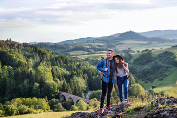 Wall Mural - young tourist couple travellers with backpacks hiking in nature, resting.