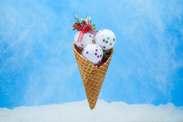 Xmas white shiny ice cream balls in waffle cone on a blue backgr