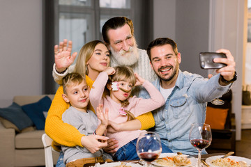 Wall Mural - Portrait of happy multi generation family taking selfie photo sitting at dinner table while celebrating holidays. thanksgiving day, birthday party