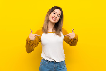 Wall Mural - Pretty young woman over isolated yellow wall proud and self-satisfied