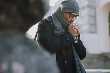 Caucasian guy blowing with warm air on his hands