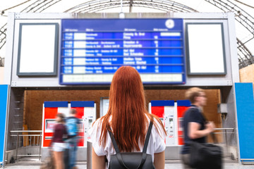 Girl looks on schedule on train station. Back view