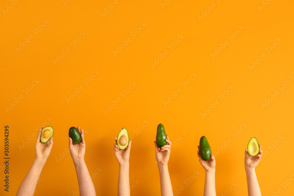 Female hands with fresh avocados on color background