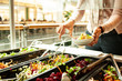 canvas print picture - Salatbuffet in einer Kantine, eine Frau bedient sich an einem Salatbuffet
