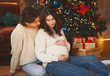 © Prostock-studio - Pregnant woman sitting by xmas tree with her husband