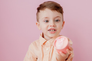 Wall Mural - Happy little boy with a gift . Photo isolated on pink background. Smiling boy holds present box. Concept of holidays and birthday