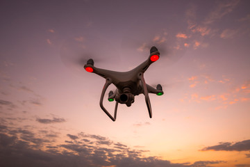 drone quadcopter with digital camera flying at sunset.Dark Flying drone and cloud sunrise sky.