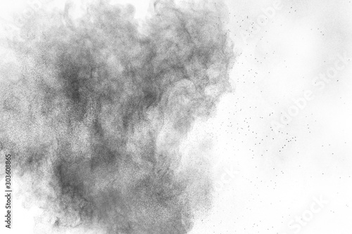 Black powder explosion against white background.Charcoal dust particles cloud...