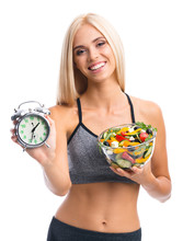 Beautiful Girl In Sportswear With Plate Of Salad And Alarm Clock, Isolated Over White Background. Young Sporty Blond Model At Studio Shot. Healthy Nutrition And Time For Dieting And Fitness Concept.