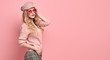 Fashionable woman in Trendy pink outfit, stylish hairstyle, makeup smiling. Young blonde in jumper, cap. Sensual beautiful model girl, stylish sunglasses, pastel fashion beauty concept on pink, banner