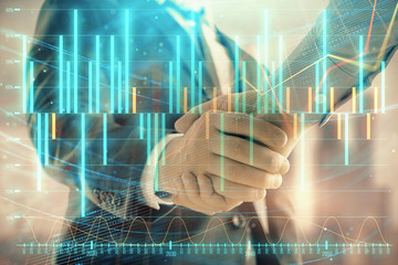 Double exposure of financial graph on cityscape background with two businessman handshake. Concept of stock market deal