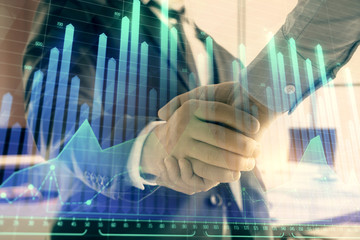 Multi exposure of financial graph on office background with two businessmen handshake. Concept of success in business